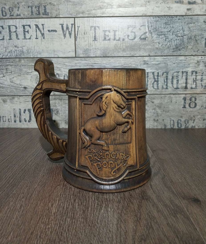 May include: A wooden beer stein with a carved horse and the words "The Prancing Pony" on the front. The stein has a brown wooden handle.