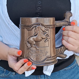 May include: A wooden beer stein with a carved horse and the words "The Prancing Pony" on the front. The stein has a brown wooden handle.