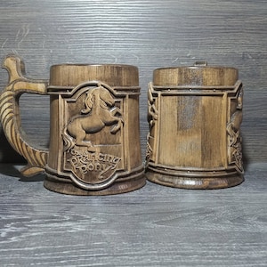 May include: Two wooden mugs, one with a carved image of a horse and the text "The Prancing Pony", the other with a carved design.