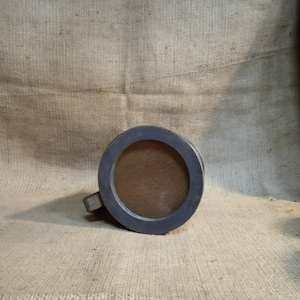 May include: A gray wooden mug with a round opening and a handle. The mug is sitting on a burlap surface.