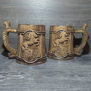 May include: Two wooden beer mugs with a brown stain. Each mug features a carved image of a horse with the text "The Prancing Pony" below it.
