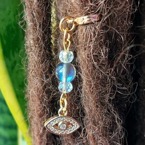 May include: Gold dreadlock bead with a blue and iridescent eye charm and clear crystal beads.