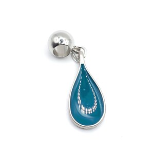May include: A silver charm with a teal blue teardrop pendant. The charm is designed to be used on a bracelet or necklace.