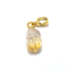 May include: A gold charm with a clear, yellow, and white gemstone pendant. The gemstone has a unique, cloudy appearance.