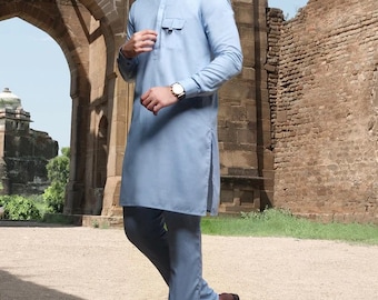 May include: A light blue long-sleeved shirt with a mandarin collar and a single pocket on the chest. The shirt is paired with matching light blue trousers and brown leather loafers.