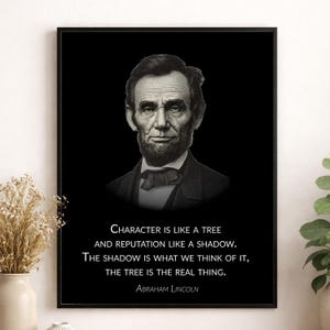 May include: A framed wall art print featuring a monochromatic portrait of Abraham Lincoln centered on a black background. Below the portrait, white text reads: Character is like a tree and reputation like a shadow. The shadow is what we think of it, the tree is the real thing. Abraham Lincoln.