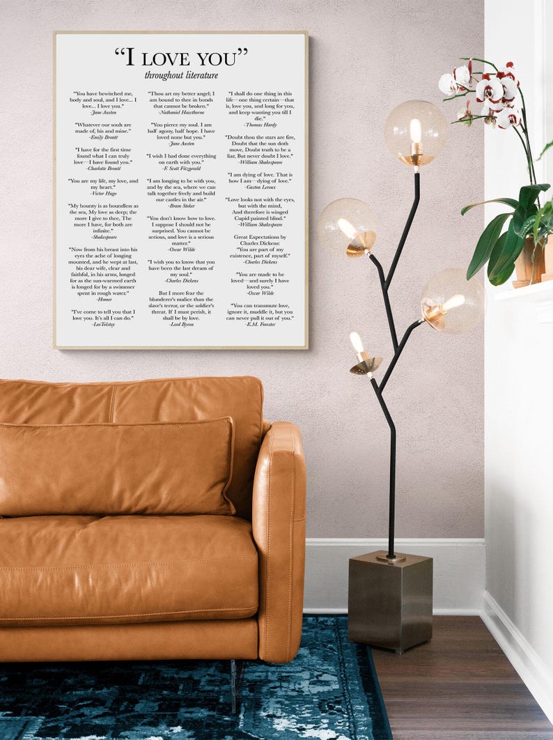 May include: A rectangular wall art print featuring the text "I LOVE YOU" throughout literature, displaying various literary quotes in black font on a white background. The print is framed in a light wood frame and hung on a wall.