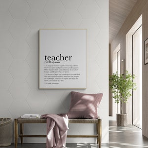 Peut inclure: Une impression encadrée blanche avec le mot "professeur" défini comme une créature magique capable de transformer la caféine en plans de cours et la patience en notes. L'impression est accrochée à un mur blanc avec un motif hexagonal.