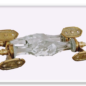 May include: A pair of crystal door handles with a faceted design and brass accents. The handles are connected by a metal bar.