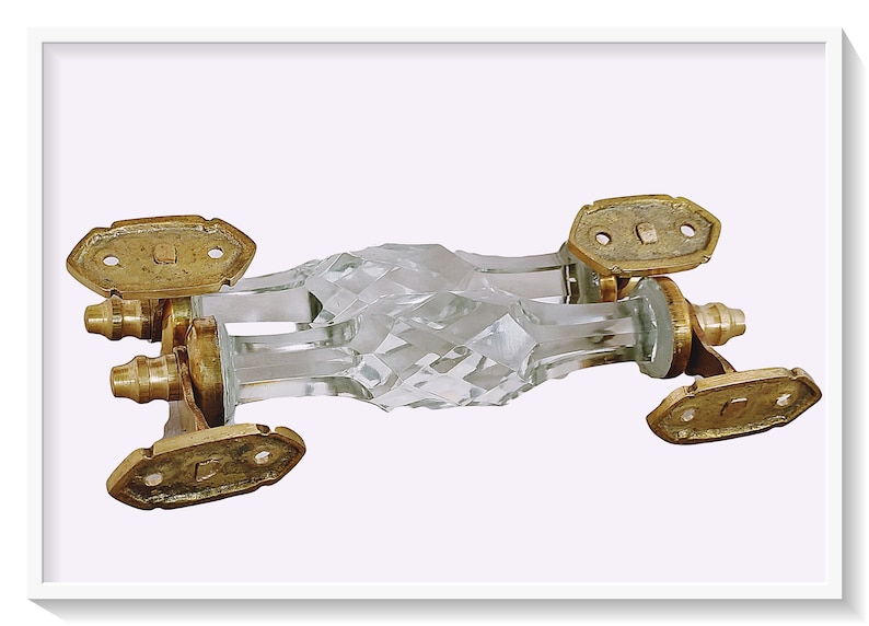May include: A pair of crystal door handles with a faceted design and brass accents. The handles are connected by a metal bar.