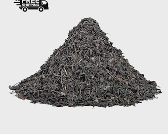 May include: A large pile of loose leaf tea, dark brown in color, against a light gray background. The tea leaves appear to be dried and finely cut. A black and white graphic of a truck with the words "FREE SHIPPING" is in the upper left corner.