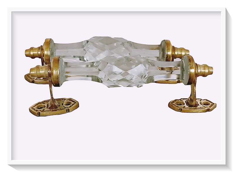 May include: A pair of clear glass door pulls with faceted edges and gold metal mounting plates.