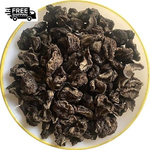 May include: A white plate with a yellow rim is filled with dried, dark brown, textured pieces. The pieces resemble dried fruit or vegetables. The image is well-lit, showing the details of the food. The food is likely a snack or ingredient.