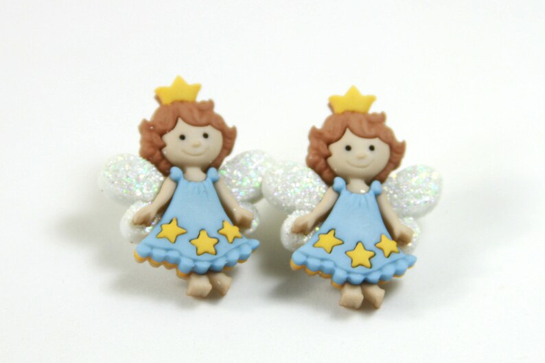 May include: Two blue fairy figurines with yellow stars and white wings. Each fairy has a gold crown and brown hair.