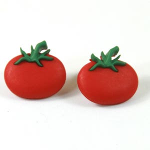 May include: A pair of red tomato-shaped earrings with green stems and leaves.