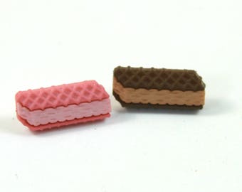 May include: Two wafer cookies, one pink and one brown, with a cream filling. The cookies are both broken in half.