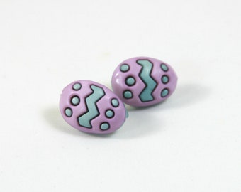 Könnte beinhalten: Zwei violette, plastikförmige Ostereierknöpfe mit einem blauen Zickzackmuster und weißen Punkten.