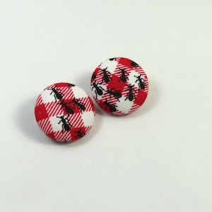 May include: A pair of red and white gingham fabric buttons with black ant silhouettes.