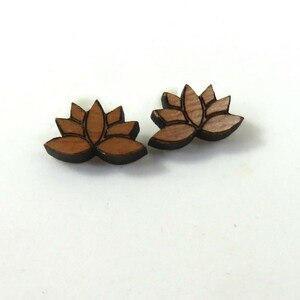 以下が含まれることがあります： 蓮の花の形をした木製のイヤリングのペア。イヤリングは茶色で、濃い茶色の輪郭があります。