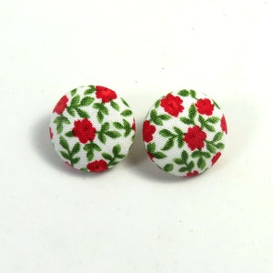 May include: A pair of red and green floral button earrings. The buttons are round and have a white background with red flowers and green leaves.