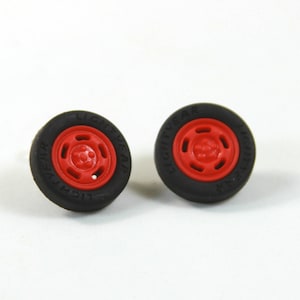 May include: A pair of red and black tire earrings. The tires are black with white lettering that says "Lightyear".
