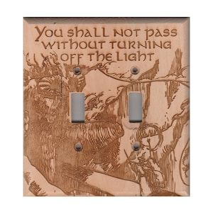 Può includere: Una placca per interruttore della luce con finitura in legno e un'immagine incisa a laser di un personaggio de Il Signore degli Anelli. Il testo "You shall not pass without turning off the light" è inciso anche sulla placca.