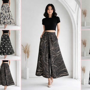 May include: A collection of wide-leg pants and skirts with various patterns. The pants and skirts are black, white, and tan with abstract, floral, and geometric designs. The model is wearing a black crop top and tan heels. The pants have pockets.