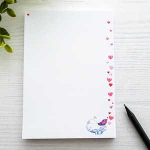 Könnte beinhalten: Ein weißer Notizblock mit einem rosa und roten Herzrand. Der Notizblock hat unten eine kleine Illustration eines Vogels und einer Wolke.