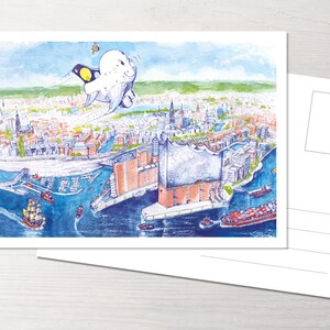 Könnte beinhalten: Eine Aquarellillustration einer Stadtkulisse mit einem fliegenden Cartoon-Seehund darüber. Der Seehund trägt einen gelben und schwarzen Hut und einen blauen Schal. Die Stadtkulisse umfasst Gebäude, Wasser und Schiffe.