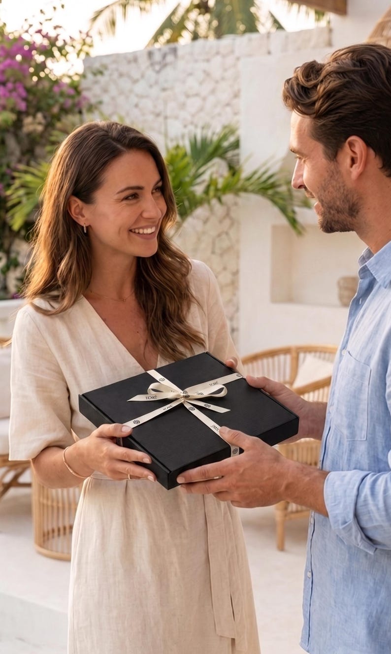 man gifting a woman TORÉ kimono robe in a black box tied with ribbon