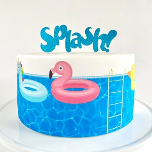 May include: A white cake decorated with a blue pool scene, featuring a flamingo float, a unicorn float, and a yellow rubber duck. The cake is topped with a blue glitter "Splash" cake topper.