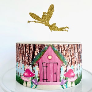 May include: A pink and green fairy house cake topper with a gold glitter fairy figurine on top. The cake is decorated with a brown tree bark pattern and green grass.