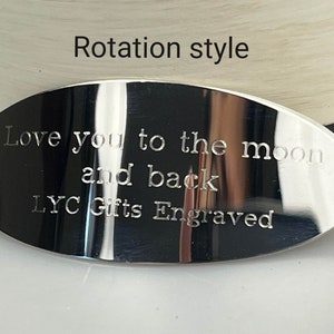 May include: A polished, oval-shaped metal plaque with engraved text. The text reads "Love you to the moon and back" and "LYC Gifts Engraved". The words "Rotation style" are above the plaque.