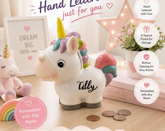 Può includere: Un salvadanaio a forma di unicorno in ceramica bianca con corno giallo, criniera e coda multicolori e il nome Tilly scritto in nero sul fianco. Il salvadanaio presenta una fessura per le monete sul dorso ed è esposto insieme ad alcune monete.