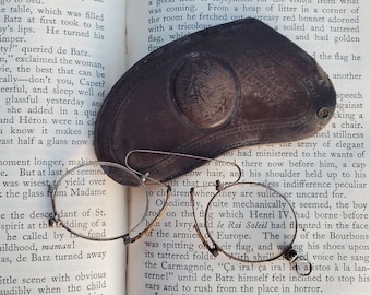 May include: Close-up of an open book with a brown leather case and a pair of eyeglasses on top. The book is titled "The Most Precious Life in Europe" and the text on the page discusses the history of France.