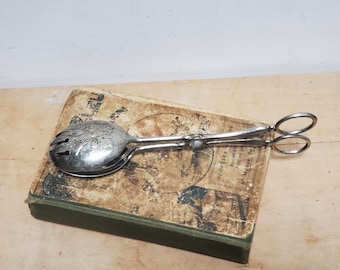 Vintage verzilverde saladetang of gebakbestek met reliëfontwerp.