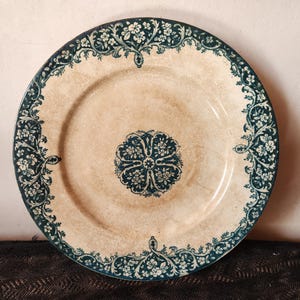 Peut inclure: Assiette en céramique de style vintage avec un centre crème et une bordure florale bleu foncé. L'assiette présente un motif floral central et des motifs complexes, idéale pour servir des aliments ou comme pièce décorative.