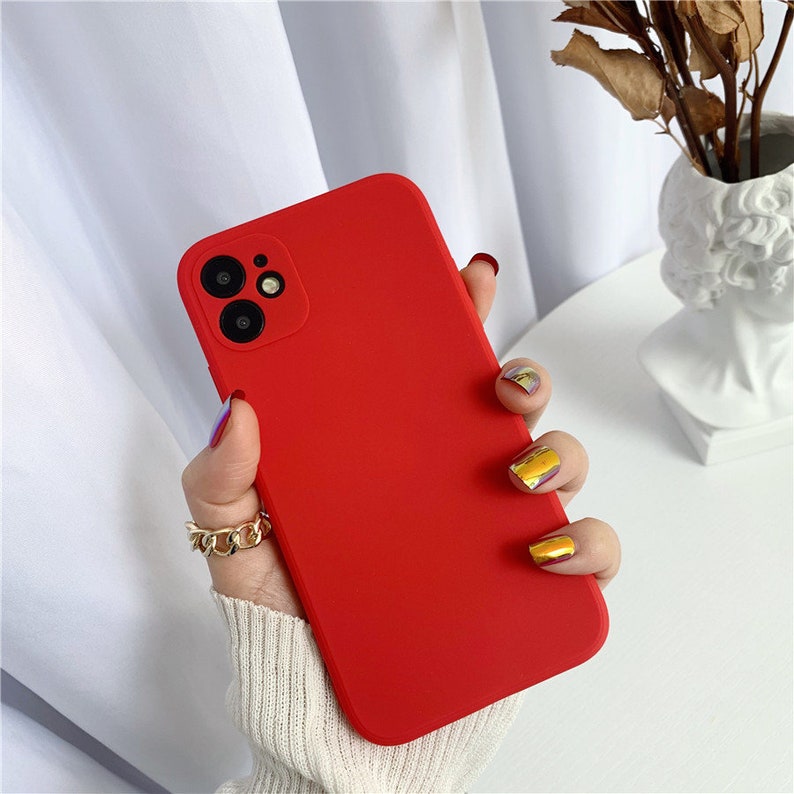May include: A bright red silicone phone case with a camera cutout for a triple lens camera.