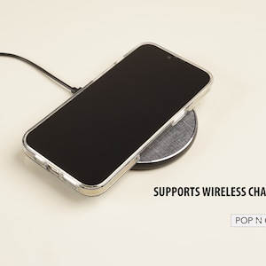 May include: A clear phone case on a wireless charging pad. The text "SUPPORTS WIRELESS CHARGING" is below the pad. The text "POP N CASES" is in a white rectangle below the text.