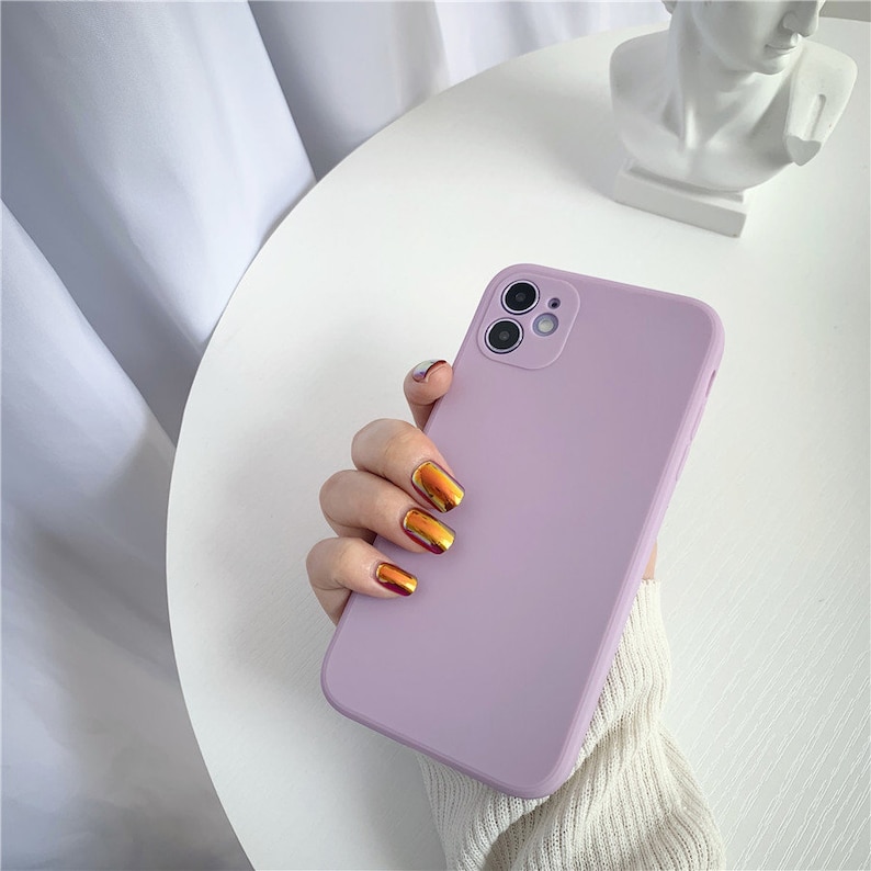 May include: A light purple phone case with a camera lens cutout. The case is made of a soft, flexible material and has a smooth finish.