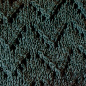 May include: A close-up of a dark green knitted fabric with a diamond pattern.