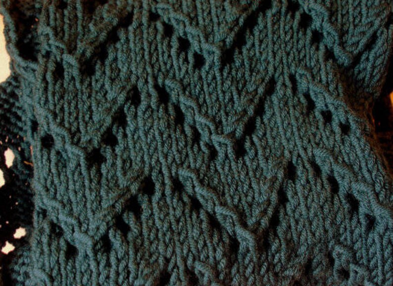 May include: A close-up of a dark green knitted fabric with a diamond pattern.