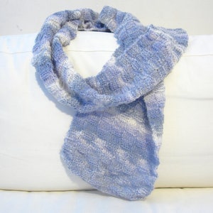K&ouml;nnte beinhalten: Ein weicher, blau-wei&szlig; gestreifter Schal aus Garn. Der Schal ist gefaltet und &uuml;ber ein wei&szlig;es Kissen gelegt.