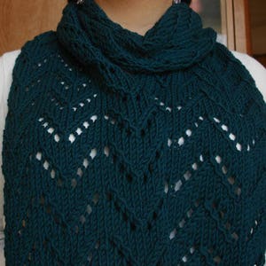 May include: A teal blue knitted scarf with a lacy pattern. The scarf is folded over and has a loose, flowing style.