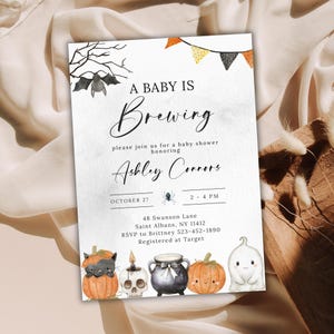 Könnte beinhalten: Eine rechteckige Babyparty-Einladungskarte mit einer Fledermaus, Wimpeln und dem Text A BABY IS BREWING, please join us for a baby shower honoring Ashley Connors, 27. Oktober, 14-16 Uhr, 48 Swanson Lane, Saint Albans, NY 11412, RSVP an Brittney 523-452-1890, Registered at Target, mit Illustrationen einer Katze im Kürbis, einer Totenkopfkerze, einem Kessel, einem Kürbis und einem Geist.