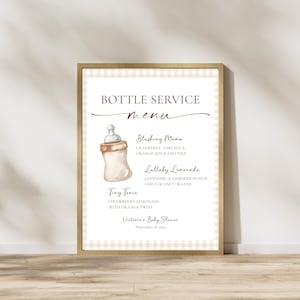 May include: A framed baby shower menu with a baby bottle illustration. The menu lists drink options: Blushing Mama, Lullaby Lemonade, and Tiny Tonic. The background has a beige gingham pattern. The text reads "Bottle Service Menu".