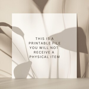 May include: A white card with the text "This is a printable file. You will not receive a physical item." The card is on a light brown surface with shadows from a plant.