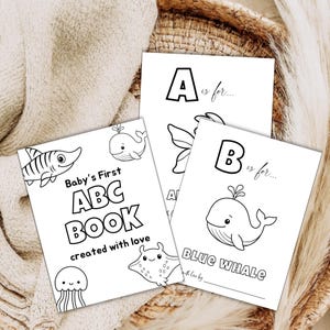 Può includere: Tre libri ABC per bambini in bianco e nero con illustrazioni di creature marine. Il primo libro recita "Baby's First ABC BOOK created with love". Gli altri libri presentano le lettere "A" e "B" con le parole "Blue Whale".