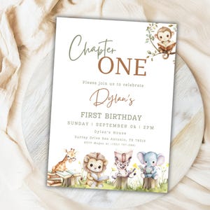 Puede incluir: Una tarjeta de invitación blanca con el texto "Chapter ONE" y "Dylan's FIRST BIRTHDAY". La tarjeta presenta ilustraciones de acuarela de animales leyendo libros, incluyendo un mono, una jirafa, un león, un leopardo y un elefante. La invitación es para un primer cumpleaños.