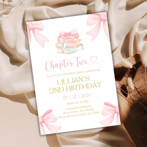 Puede incluir: Una invitación de cumpleaños rosa y blanca con una pila de libros y un lazo. La invitación dice "Capítulo Dos" y es para el segundo cumpleaños de Lillian. La fiesta es el 12 de julio de 2024 a las 2:00 PM en 14 Bloom Street, Wenatchee, WA 98801. RSVP a Alyssa al (857) 411-7890.